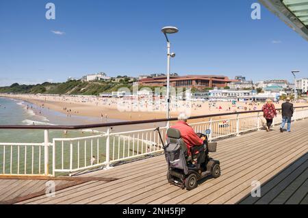 BOURNEMOUTH, Großbritannien - 08. Juli 2022. Ein alter Mann auf einem Roller an der Promenade des Bournemouth Pier, Dorset, Großbritannien. Alter und Behinderung Stockfoto