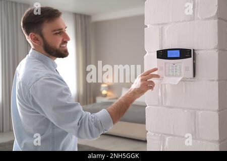 Ein Mann, der zu Hause einen Code für die Alarmanlage eingibt Stockfoto