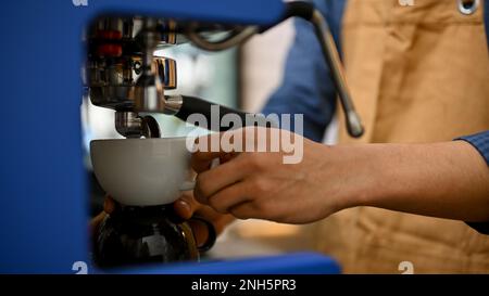 Ein männlicher Barista bereitet Kaffee mit einer Espressomaschine zu, bereitet die Bestellung des Gastes vor, arbeitet im Café. Zugeschnittenes Bild Stockfoto