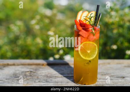 Ein Glas grüner tropischer Tee mit Limette, Orange, Wassermelone und Apfel vor grünem Sommerhintergrund Stockfoto