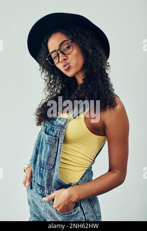 Schlau und frech. Studiofoto einer attraktiven jungen Frau, die vor grauem Hintergrund posiert. Stockfoto