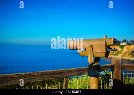 An einem hellen, wolkenlosen Tag bietet ein Teleskop für Seher und Touristen einen Blick auf den tiefen blauen Ozean vor der kalifornischen Küste. Stockfoto