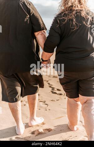 Ein Paar, das beim Spazierengehen am Strand Händchen hielt. Schließen. Sommerzeit Stockfoto