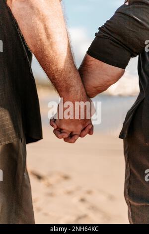 Ein Paar, das beim Spazierengehen am Strand Händchen hielt. Schließen. Sommerzeit Stockfoto