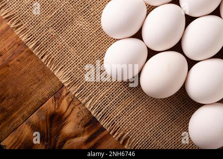 Weiße Hühnereier auf Leinenstruktur. Sehr beliebtes nahrhaftes und wirtschaftliches Lebensmittelprodukt. Obere Tabellenansicht. Polizisten-Raum. Stockfoto