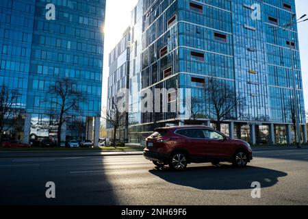 Danzig Polen - Mai 2022 Sun geht durch die Wolkenkratzer-Szene des öffentlichen Verkehrs in Danzig. Oliva Geschäftsviertel Transport Stadtverkehr. Straßenbahnen Busse Autos City Traffic Jam. Stadtleben Stockfoto