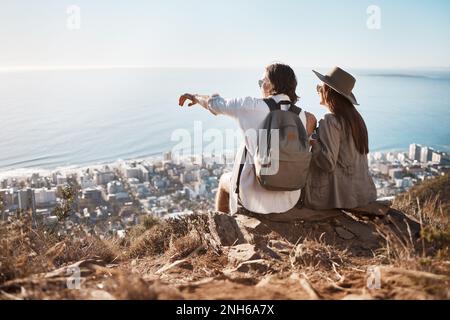 Zeigen, Blick und Paaren auf einem Berg zum Wandern, Reisen und Trekking in der Schweiz. Entspannen, Abenteuer und Mann und Frau sitzen auf einer Klippe und schauen Stockfoto