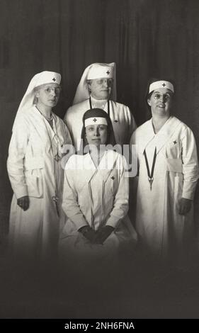 Erster Weltkrieg Postkarte mit einem Schwarzweißfoto von vier Krankenschwestern (Kanadier?) In Uniform. Einer sitzt vorne, drei stehen neben ihr. Sie tragen rote, kreuzverzierte Kopftücher. 1917-1918 Stockfoto