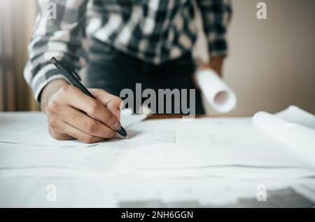 Nahaufnahme eines asiatischen Bauingenieurs, der an einem Bauprojekt auf der Baustelle am Arbeitsplatz im Büro arbeitet. Stockfoto
