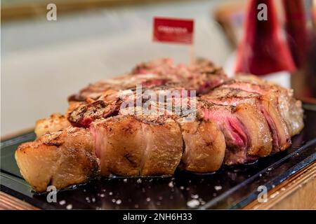 Klassisches gebratenes, trockenes, gereiftes T-Bone Florentiner Steak von einer Chianina-Kuh, die in einem Restaurant in Florenz, Italien, auf einer Servierplatte vom Grill dampft Stockfoto