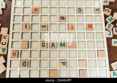 Auf dem Holztisch verstreute Scrabble-Fliesen - das Spielwort wurde aus den Fliesen geschrieben. Hochwertiges Foto Stockfoto