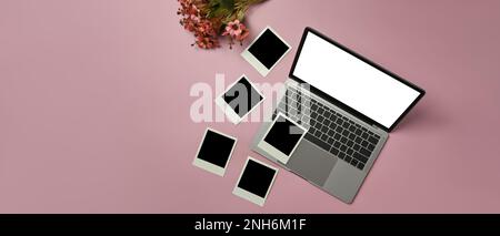 Laptop mit weißem Bildschirm, leeren Bilderrahmen und einem wunderschönen Blumenstrauß auf pinkfarbenem Hintergrund Stockfoto