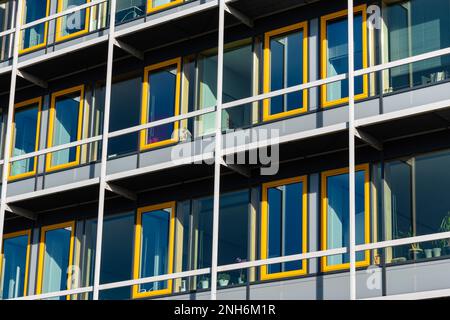 Bruchteil der Fassade des Gebäudes mit rechteckigen gelben Fenstern. Stockfoto