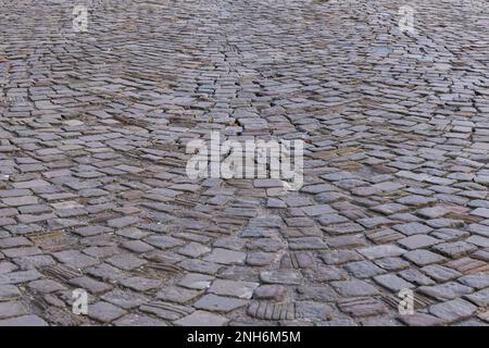 Blick von oben auf eine alte gepflasterte Straße mit Kopfsteinpflaster. Nahaufnahme des Hintergrunds. Stockfoto