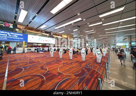 Selbstbedienungsschalter in der Abflughalle von Terminal 1, Flughafen Singapur Changi, mit Gepäckabgabeschalter links, Februar 2023 Stockfoto