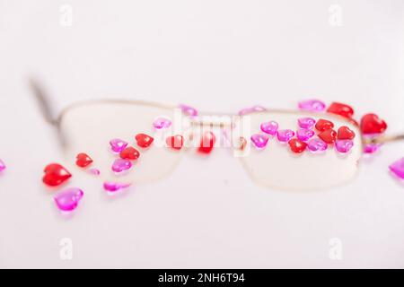 Tabletten, Kapseln zum Sehen. Vitamine in Form von Herzen mit Brille auf weißem Hintergrund. Dioptrien, Myopie, Weitsicht. Augenarzt, Optiker, Augengesundheit. Hochwertiges Foto Stockfoto