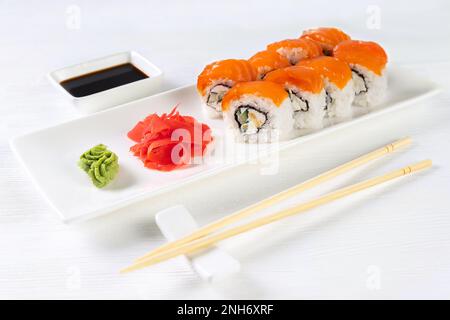 Sushi Roll Philadelphia mit Lachs, geräuchertem Aal, Avocado, Frischkäse auf weißem Hintergrund. Sushi-Menü, Brötchen auf weißem Gericht mit Wasabi und Ingwer Stockfoto