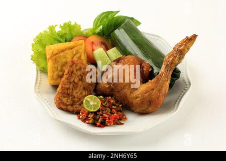 Nasi Timbel Komplit, traditioneller Sundanesischer Reis mit Bananenblatt, serviert mit gebratenem Hähnchen, Tempeh, Tofu und Chilipaste Stockfoto