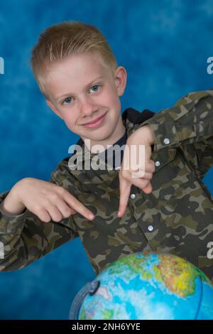 Ein kleiner Junge, der eine moderne Erdkugel zeigt Stockfoto