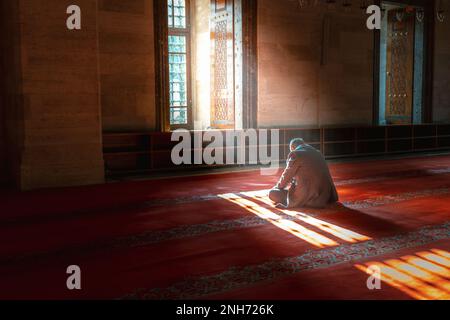 Islamisches Foto. Muslimischer Mann betet in der Moschee. Sonnenstrahlen und Dunst durch das Fenster. Ramadan- oder islamisches Konzeptfoto mit Kopierbereich für Texte Stockfoto