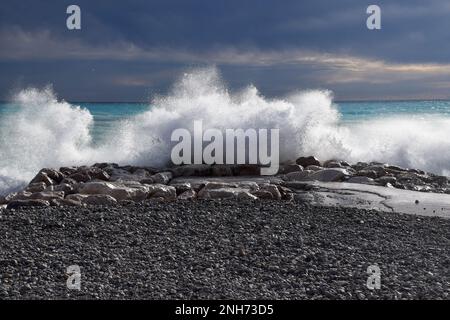 Am Strand spritzen Wellen gegen Felsen Stockfoto