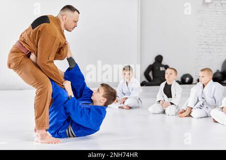 Lehrer, Profi-Judo, Jiu Jitsu-Trainer-Trainingstypen, Jungs, zeigen Übungen. Aufmerksamkeit, Stärke, Macht Stockfoto