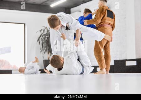 Profisportübungen. Jungs, Kinder im weißen Kimono-Training, Judo-Übungen, Jiu-Jitsu-Übungen drinnen Stockfoto
