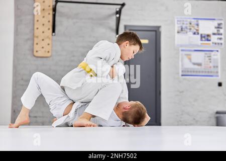 Zukünftige Sportler. Jungs, Kinder im weißen Kimono-Training, Judo-Übungen, Jiu-Jitsu-Übungen drinnen Stockfoto