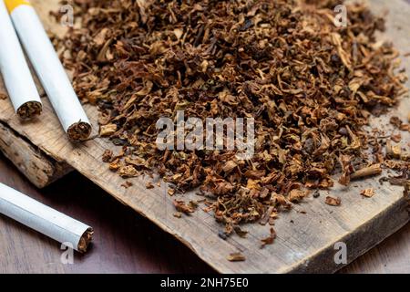 Tabakblätter und handgemachte Zigaretten auf Holzhintergrund Stockfoto