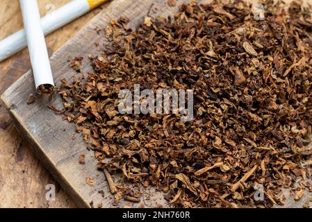 Tabakblätter und handgefertigte Zigaretten auf Holzhintergrund mit Blick von oben Stockfoto