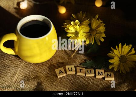 eine tasse Kaffee im Herbst mit Blättern und Blumen. Text Herbst Stockfoto
