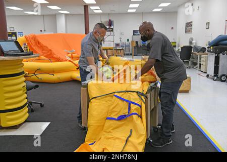 Matthew Miller, links, 572nd Commodities Maintenance Support Squadron Life Support Survival Equipment Repairer, und Victor Ware, 572nd Commodities Maintenance Support Squadron Life Support Work Repairer, packen ein 20-Mann-Rettungsfloß in eine Kiste auf der Robins Air Force Base, Georgia, 20. Juli 2022. Sobald sich das Floß in der Kiste befindet, wird es mehrere Stunden in einen Ofen gestellt, um das Material aufzuweichen. 20-Mann-Rettungsinsel, lebenserhaltende Überlebensausrüstung, Stockfoto