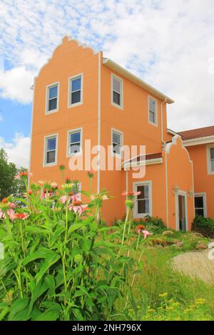Montebello Bed & Breakfast Inn am Morgen mit rosa Maisblumen im Vordergrund und Wolken mit blauem Himmel Stockfoto