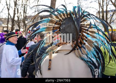 München, Deutschland. 21. Februar 2023. Ein Mann mit Federn auf dem Kopf steht auf dem Tanz der Marktfrauen auf dem Viktualienmarkt am Shrove-Dienstag. Kredit: Peter Kneffel/dpa/Alamy Live News Stockfoto