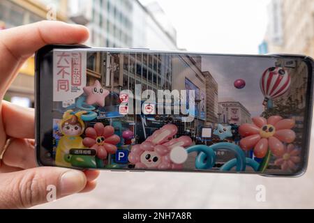 SHANGHAI, CHINA - 21. FEBRUAR 2023 - Ein Tourist verwendet die App „Play Nanbujie“ auf der Nanjing Road Pedestrian Street in Shanghai, China, 21. Februar 2023. Stockfoto