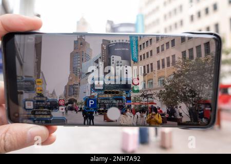SHANGHAI, CHINA - 21. FEBRUAR 2023 - Ein Tourist verwendet die App „Play Nanbujie“ auf der Nanjing Road Pedestrian Street in Shanghai, China, 21. Februar 2023. Stockfoto