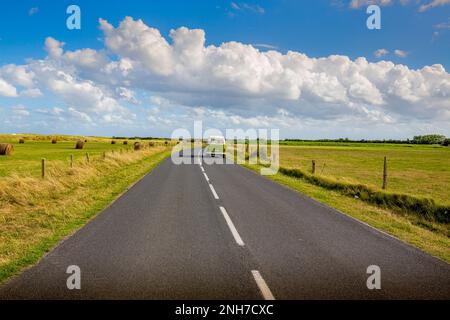 BARFLEUR, FRANKREICH - SEPTEMBER CIRCA, 2020. Straße in der Mitte der natürlichen Landschaft mit einem Van auf der langen Straße mit blau bewölkten Himmel Hintergrund. Stockfoto