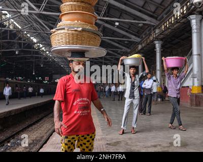 Torhüter in Chhatrapati Shivaji Maharaj Terminus (Csmt) in Mumbai, Indien, die Körbe mit Fischen auf dem Kopf einen ankommenden Zug zu liefern Stockfoto