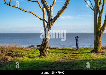 Walker blickt auf das Meer mit einem Fernglas von Walton on the Naze Stockfoto