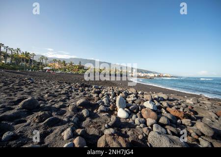 Ebbe am schwarzen Sandstrand in Playa Jardin Puerto de la Cruz, Teneriffe, Kanarische Inseln, Spanien, Tourismus, Wintersonne. Vulkangestein. Stockfoto