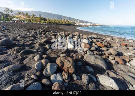 Ebbe am schwarzen Sandstrand in Playa Jardin Puerto de la Cruz, Teneriffe, Kanarische Inseln, Spanien, Tourismus, Wintersonne. Vulkangestein. Stockfoto