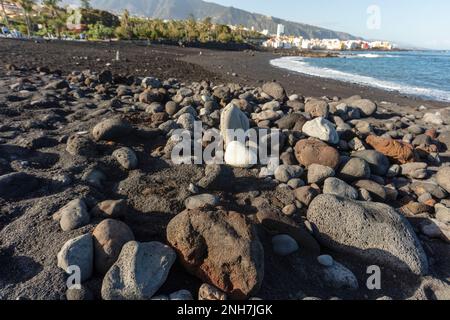 Ebbe am schwarzen Sandstrand in Playa Jardin Puerto de la Cruz, Teneriffe, Kanarische Inseln, Spanien, Tourismus, Wintersonne. Vulkangestein. Stockfoto