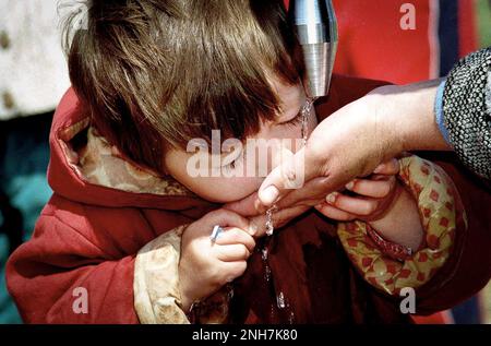 Leonora Kozmaqi im Alter von 2 Jahren trinkt Wasser aus der Hand ihrer Mutter, während es im Flüchtlingslager Brazda in Mazedonien am 1999. April aus einem Standrohr strömt. Das Lager wurde von der NATO geleitet, aber an UNHCR übergeben.Leonora Kozmaqi, die während des Kosovokriegs 1999 in einem Flüchtlingslager in Mazedonien fotografiert wurde. Die Fotografin Gary Roberts verfolgte Leonora 21 Jahre später über Linkedin zum Weltflüchtlingstag, um herauszufinden, was aus ihrem Leben geworden war. Jaya Narain, die auch über die Flüchtlingskrise berichtet hatte, sprach mit Leonora, um zu erfahren, wie sie überlebt und ihr Leben verändert hatte. Abbildung garyrobertsphotography.com Stockfoto