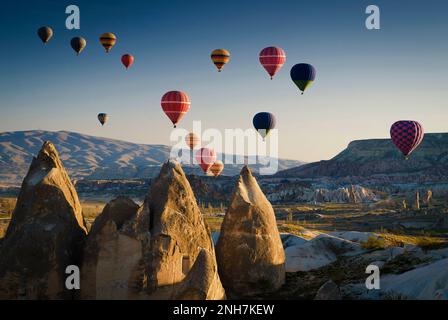 Bunte Heißluftballons, die über dem Goreme Historical National Park, Goreme, Kappadokien, Türkei, aufsteigen Stockfoto