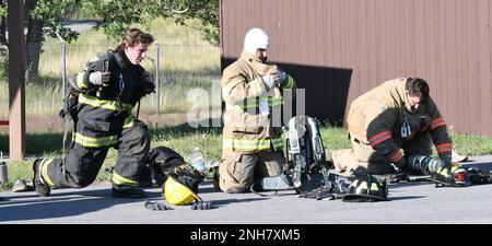 Die Geräusche von Kettensägen, die in Holz zerrissen wurden, und von Brechstangen, die eine Metalltür öffneten, hallten bis in den Abend, während die örtlichen freiwilligen Feuerwehrleute am 21. Juli in der Ausbildungseinrichtung der Feuerwehr und der Rettungsdienste von Fort Drum ihr Handwerk übten. Vierzehn Auszubildende aus mehreren Feuerwehren von Jefferson County nehmen an der vom New Yorker State Office of Fire Prevention and Control (OFPC) durchgeführten Schulung zur internen Brandbekämpfung Teil. (Foto von Mike Strasser, Fort Drum Garrison Public Affairs) Stockfoto