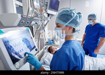 Krankenhauspfleger überprüfen auf der Intensivstation die Patientinnen und überwachen ihre Gesundheit mit medizinischen Geräten und Sensoren. INTENSIVSTATION Stockfoto