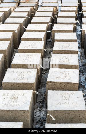 Porträtblick auf Rock Bolder. Betonwürfel über Blockhintergrund. Vier quadratische Betonblöcke hintereinander Stockfoto