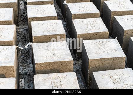 Betonwürfel über Blockhintergrund. Waghalsiger. Vier quadratische Betonblöcke hintereinander Stockfoto