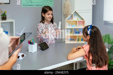 Schüler zeigen Glühbirne und LED-Lampe in Ökologie Klassenzimmer Stockfoto