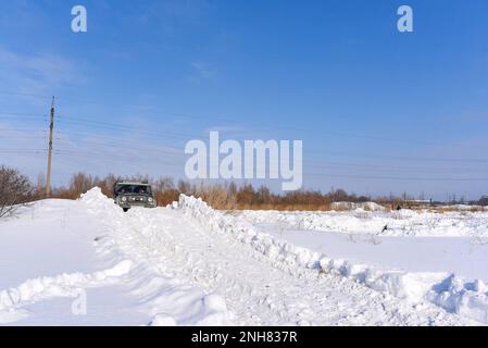 Der russische Offroad-SUV „UAZ Junter 469“ fährt im Geländewagen im Winter auf einem Feld auf einer schlechten Straße auf einem schneebedeckten Berg. Stockfoto